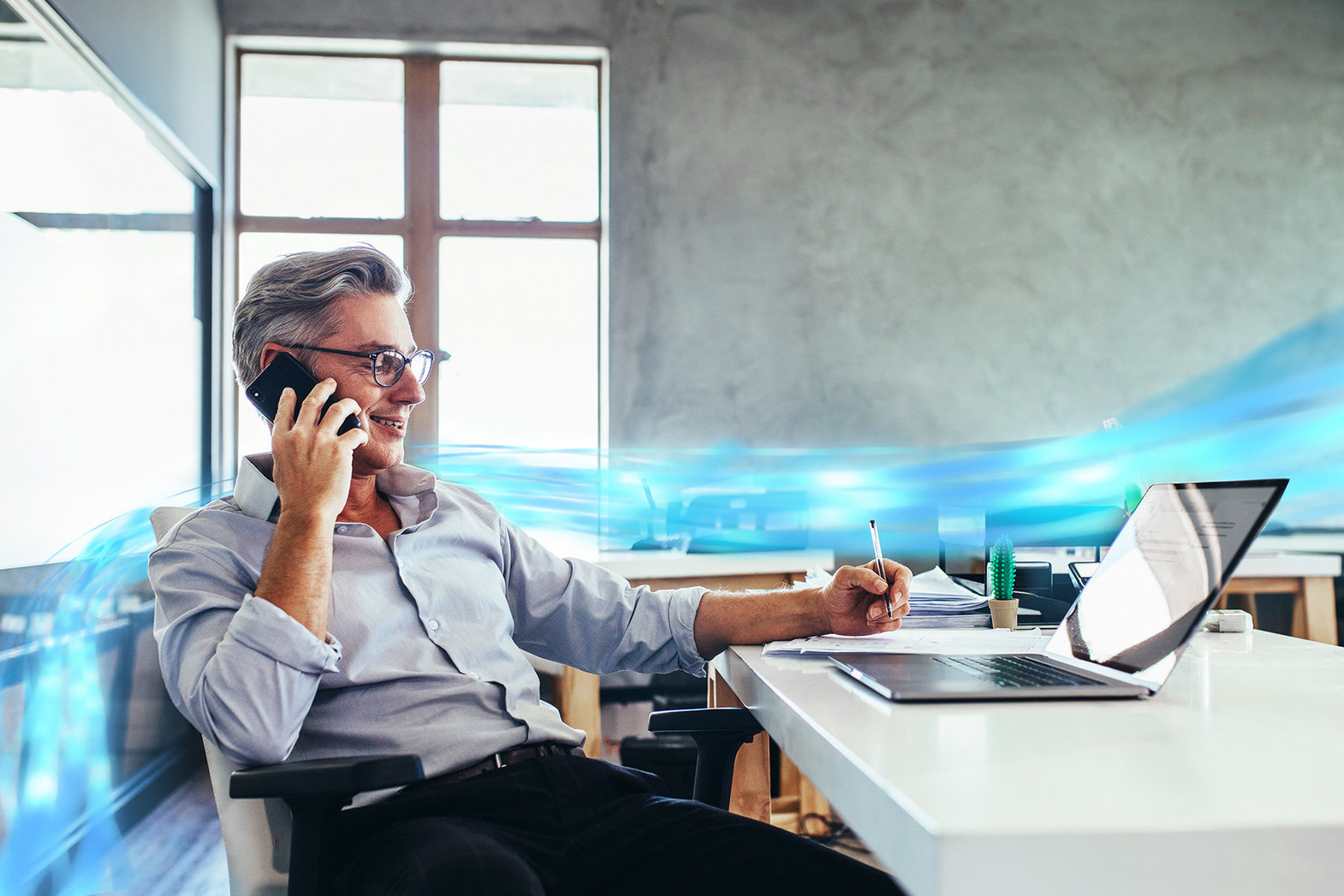 Ein Geschäftsmann, der telefoniert und am Laptop arbeitet