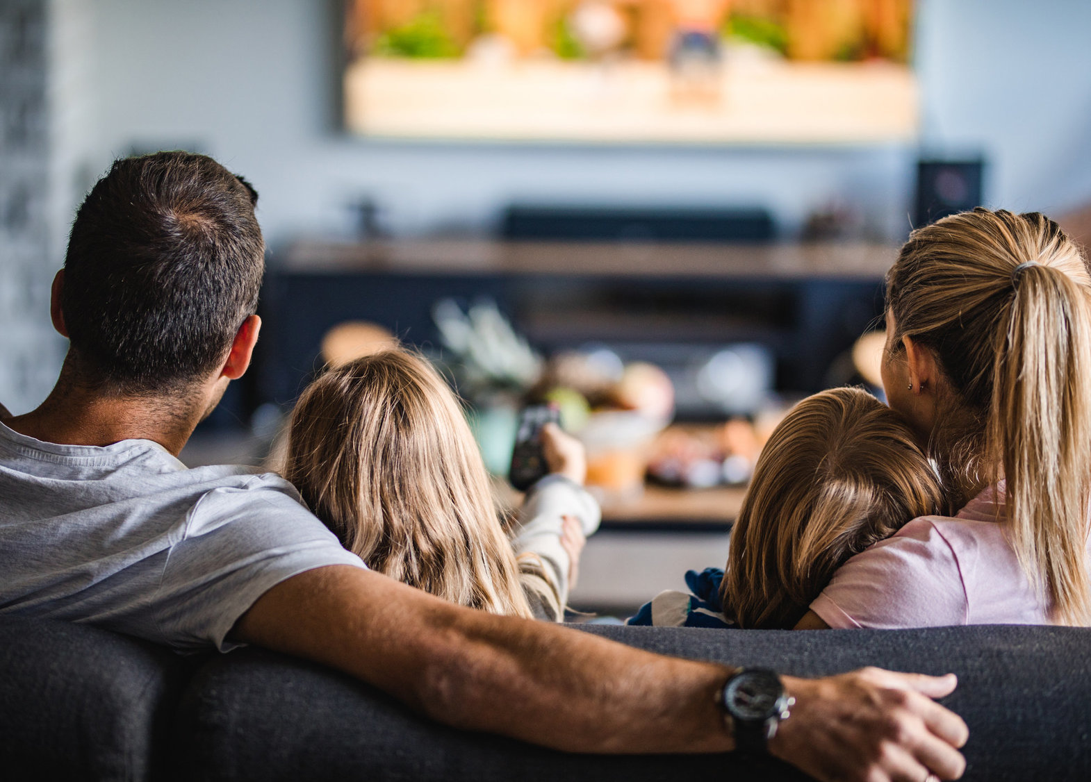 Eine Familie, die im Wohnzimmer Fernsehen schaut